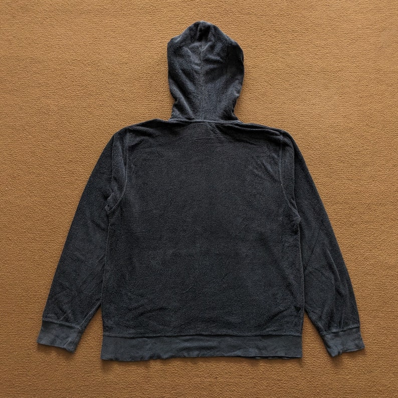 Op de afbeelding: Een donkergrijze hoodie met een rits. De hoodie is gemaakt van een zachte, textuurrijke stof.