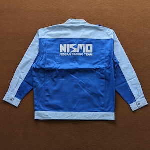 May include: A blue and light blue workwear style jacket with the NISMO logo and the text "NISSAN RACING TEAM" on the back.