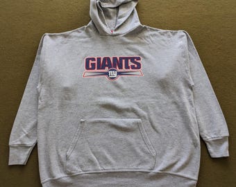 May include: A gray hooded sweatshirt with a large blue and red "Giants" logo with a smaller blue and red "NY" logo inside a circle. The sweatshirt has a front pocket.