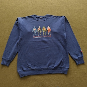 May include: Navy blue sweatshirt with a crew neck and long sleeves. The front features a graphic of four figures with the letters "F.U.C.C." above the words "Guerrilla Warfare". The Champion logo is visible on the left sleeve.