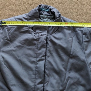 May include: A gray, long-sleeved jacket with a stand-up collar and a button closure. The jacket has a label that reads "7 for all mankind".