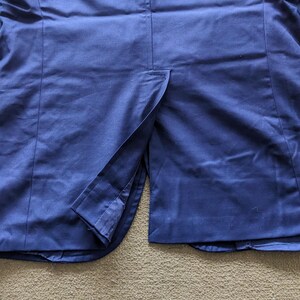 Puede incluir: Primer plano de una blazer azul marino, mostrando la textura de la tela y la abertura trasera. La prenda est&aacute; hecha de un material liso, con costuras visibles y un dise&ntilde;o elegante.