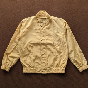 May include: A yellow lightweight jacket with a snap closure and a ribbed waistband.
