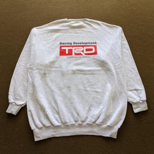 May include: Gray sweatshirt with a red "TRD" logo and the text "Racing Development Toyota Motor Sports."