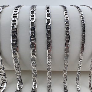 Puede incluir: Un conjunto de seis collares de cadena marinera plateados de diferentes longitudes. Las cadenas están hechas de un metal grueso y duradero y tienen un diseño clásico y náutico.