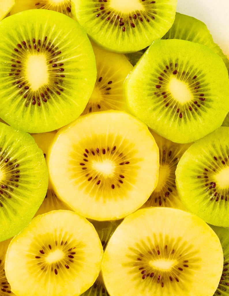 May include: A collection of sliced kiwi fruit arranged in a dense pattern. The slices display vibrant lime green and pale yellow flesh with small, dark black seeds radiating from the centre of each piece, creating a bright, textured composition.
