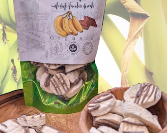 May include: A shiny green resealable pouch of freeze-dried bananas with dark chocolate drizzle. The label reads Nature in its purest form, Freeze Dried Bananas with dark chocolate drizzle, Organic, Gluten Free, Non GMO, and No Added Sugars.