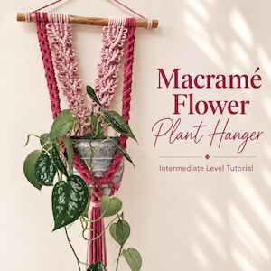 May include: A macramé plant hanger featuring dark pink and light pink knotted cord suspended from a wooden dowel, holding a gray pot with a green variegated pothos plant. Text reads: Macramé Flower Plant Hanger, Intermediate Level Tutorial.
