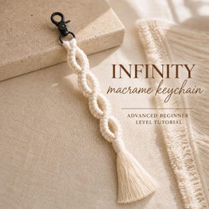 Può includere: Un portachiavi in macramè color bianco sporco con un motivo a nodi infiniti ripetuti, rifinito con una nappa sul fondo e un moschettone in metallo nero sulla parte superiore. Il testo recita INFINITY macrame keychain ADVANCED BEGINNER LEVEL TUTORIAL.
