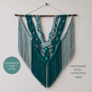 May include: A teal macramé wall hanging with a geometric design, featuring a wooden dowel at the top. The wall art has a layered pattern with fringe and decorative elements in shades of teal and light blue. The text "Intermediate Level" is on a teal circle.