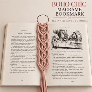 Puede incluir: Un marcapáginas de macramé rosa empolvado con un patrón de celosía anudado y una borla larga, unido a un anillo metálico circular. El marcapáginas está sobre un libro abierto con el texto BOHO CHIC MACRAME BOOKMARK BEGINNER LEVEL TUTORIAL.