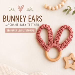 May include: A macrame baby teether featuring a smooth, round wooden ring with two knotted, dusty rose-colored fabric loops shaped like bunny ears. The text reads BUNNEY EARS MACRAME BABY TEETHER BEGINNER LEVEL TUTORIAL with a heart and leaf graphic.