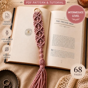 Pode incluir: Um marcador de macramé rosa empoeirado com um anel de madeira e borla, num livro aberto. O texto na imagem diz "Macrame Bookmark PDF Pattern & Tutorial" e "Intermediate Level". O livro está aberto com o título "The Trojan War".