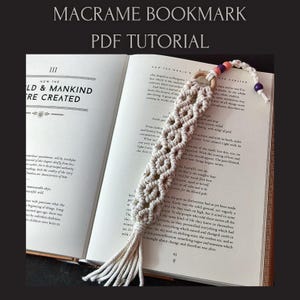 Può includere: Un segnalibro in macramè color crema con un motivo intrecciato, ornato da perline di legno e un nappa. Il segnalibro è posto in un libro aperto con il titolo "How the World & Mankind Were Created" e il testo "Macrame Bookmark PDF Tutorial".