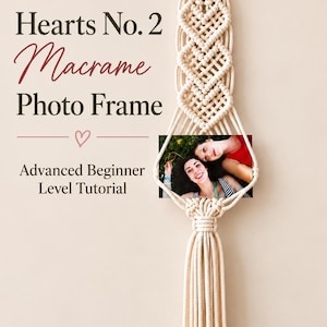 May include: A cream-colored macrame wall hanging featuring a heart-shaped woven pattern, a wooden ring at the top, and a long tassel at the bottom. The text reads: Hearts No. 2 Macrame Photo Frame, Advanced Beginner Level Tutorial.