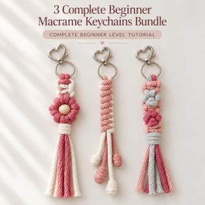 Può includere: Tre portachiavi in macramè con chiusure argentate a forma di cuore. A sinistra un fiore rosa con una perla di legno al centro e una nappa. Al centro un motivo a nodi a spirale. A destra un design a forma di zampa con una nappa.