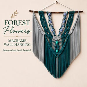 Puede incluir: Un tapiz de macramé hecho con cuerda de color verde azulado oscuro y gris claro, colgado de una rama de madera. El diseño incluye nudos intrincados, cuentas esféricas azul claro y dos cuentas verde brillante. Texto: Forest Flowers Macrame Wall Hanging Intermediate Level Tutorial.