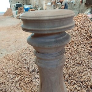 Puede incluir: Primer plano de una pata de mesa de madera con tallas intrincadas. La pata est&aacute; hecha de madera marr&oacute;n claro y tiene un acabado liso y pulido. La pata est&aacute; rodeada de virutas de madera.
