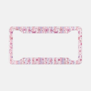 May include: A rectangular license plate frame featuring a repeating pattern of pink and purple butterflies and small flowers set against a background of vertical stripes in soft pastel shades of pink, lavender, and white with four mounting holes.