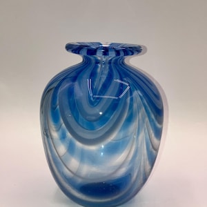 May include: A blue and white glass vase with a swirling pattern. The vase is round and has a wide mouth.