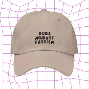 Może przedstawiać: Beżowa czapka z daszkiem z czarnym haftem z napisem "DOGS AGAINST FASCISM".