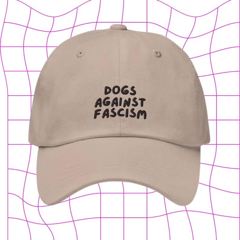 Może przedstawiać: Beżowa czapka z daszkiem z czarnym haftem z napisem "DOGS AGAINST FASCISM".
