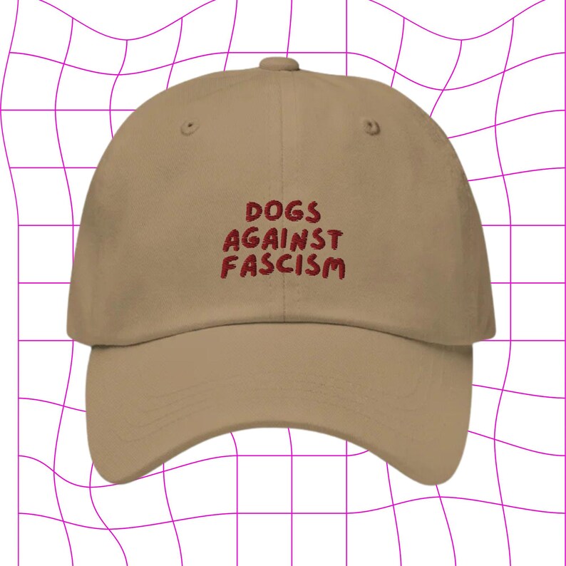 Może przedstawiać: Beżowa czapka z daszkiem z haftem "DOGS AGAINST FASCISM" w kolorze czerwonym z przodu.