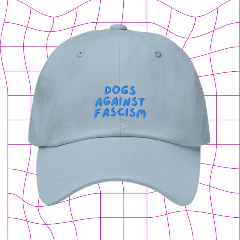 Może przedstawiać: Jasnoniebieska czapka z daszkiem z haftem "DOGS AGAINST FASCISM" w kolorze niebieskim.