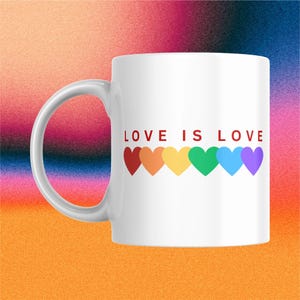 May include: White ceramic mug with the text "LOVE IS LOVE" in red letters. Below the text are six colorful hearts in a rainbow pattern. The mug has a curved handle and is set against a colorful gradient background.