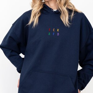 May include: A navy blue hooded sweatshirt with a rainbow embroidered design that spells out "FCK AFD".