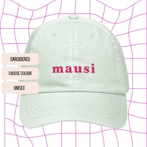 May include: A white baseball cap with the word "mausi" embroidered in pink on the front.