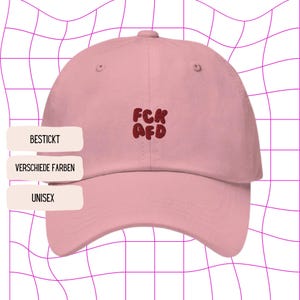 Könnte beinhalten: Rosa Baseballkappe mit einem roten gestickten Design, das "FCK AFD" sagt. Die Kappe ist in verschiedenen Farben erhältlich und ist unisex.