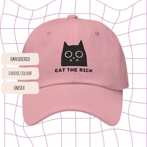 Op de afbeelding: Roze baseballpet met een geborduurde zwarte kat met een bril en de tekst "Eat the Rich".