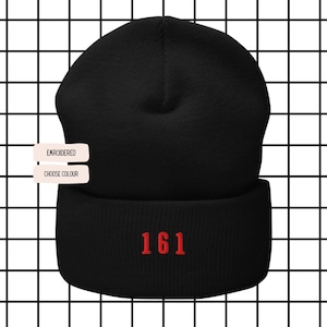 May include: Black beanie hat with a folded brim. The number "161" is embroidered in red on the front. The background is a grid pattern of black lines on a white background. The words "EMBROIDERED" and "CHOOSE COLOUR" are on the left.