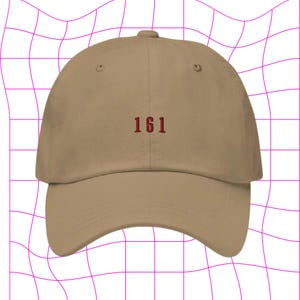 May include: A tan baseball cap with the number "161" embroidered in red on the front.