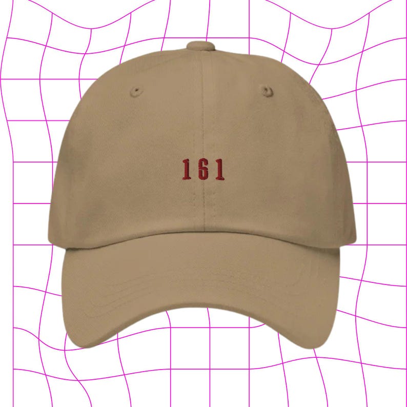 May include: A tan baseball cap with the number "161" embroidered in red on the front.