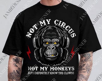 May include: Black t-shirt featuring a gorilla wearing headphones, with the text "NOT MY CIRCUS, NOT MY MONKEYS BUT I DEFINITELY KNOW THE CLOWNS." The design includes a red lightning bolt on each side of the gorilla's head. The gorilla has yellow eyes.
