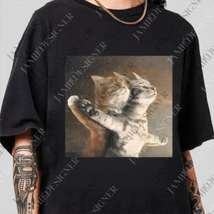 A black t-shirt with a printed image of two cats sitting together.