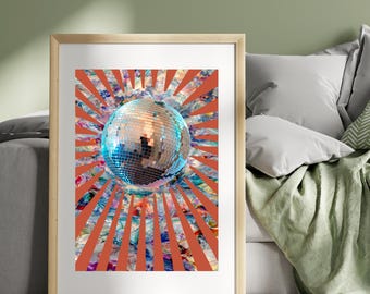 May include: Framed art print showing a disco ball with a mirrored surface, set against a vibrant, colourful background of orange rays and abstract patterns. The artwork is displayed in a light-coloured wooden frame.