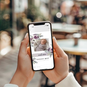 May include: A phone screen displaying a welcome announcement for a baby girl named Violet May. The announcement features a floral design with purple and white flowers and a photo of the baby in a white and purple swaddle.
