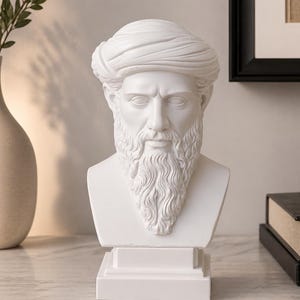 May include: A white bust of a man with a long beard and a turban-like head covering. The sculpture is on a rectangular base and sits on a marble surface. The bust is a decorative item, likely for home decor.