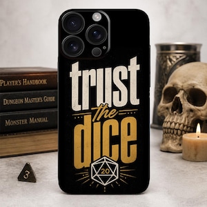 May include: Black phone case with the text "trust the dice" in white and gold. The design includes a D20 die graphic. The case is next to a stack of books, a skull, and a lit candle, suggesting a tabletop gaming theme.