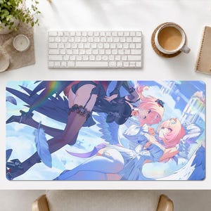 Puede incluir: Una alfombrilla de escritorio rectangular con una vibrante ilustración de estilo anime de dos personajes con cabello rosa y alas sobre un cielo azul. Un personaje viste un conjunto negro con medias oscuras, mientras el otro lleva un vestido blanco con detalles azules.
