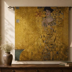 May include: A rectangular wall tapestry featuring a reproduction of Gustav Klimt's Portrait of Adele Bloch-Bauer I. The artwork displays a figure in a gold-toned gown with geometric patterns, suspended from a dark metal rod with decorative finials.