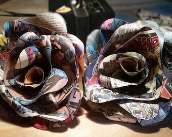 Puede incluir: Dos rosas de papel hechas a mano a partir de páginas de cómics. Las rosas son de color rojo oscuro, azul y amarillo. Las rosas son una forma única y creativa de añadir un toque de fantasía a cualquier decoración.