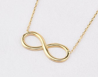 May include: A gold infinity symbol necklace on a white background.