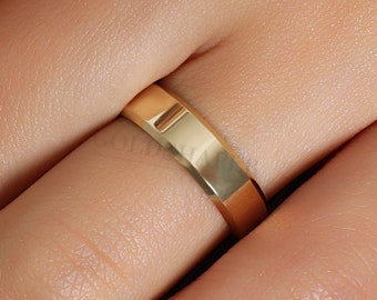 May include: A simple gold wedding band with a slightly rounded edge.