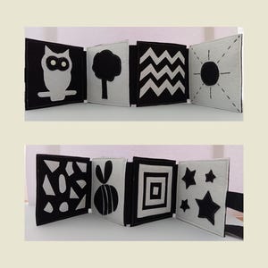 Puede incluir: Libro de fieltro blanco y negro para bebés con diferentes formas y patrones. Las páginas presentan un búho, un árbol, zigzags, un sol, formas geométricas, una abeja, un cuadrado y estrellas.