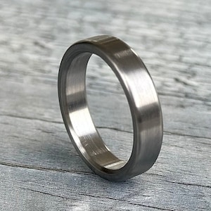 May include: A brushed silver wedding band with a flat, wide profile.