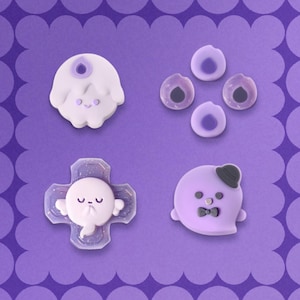 May include: A set of four purple and lavender decorative charms featuring a ghost with a candle flame, four small circular accents, a ghost with wings on a cross-shaped base with glitter, and a ghost wearing a black bowler hat and bowtie.